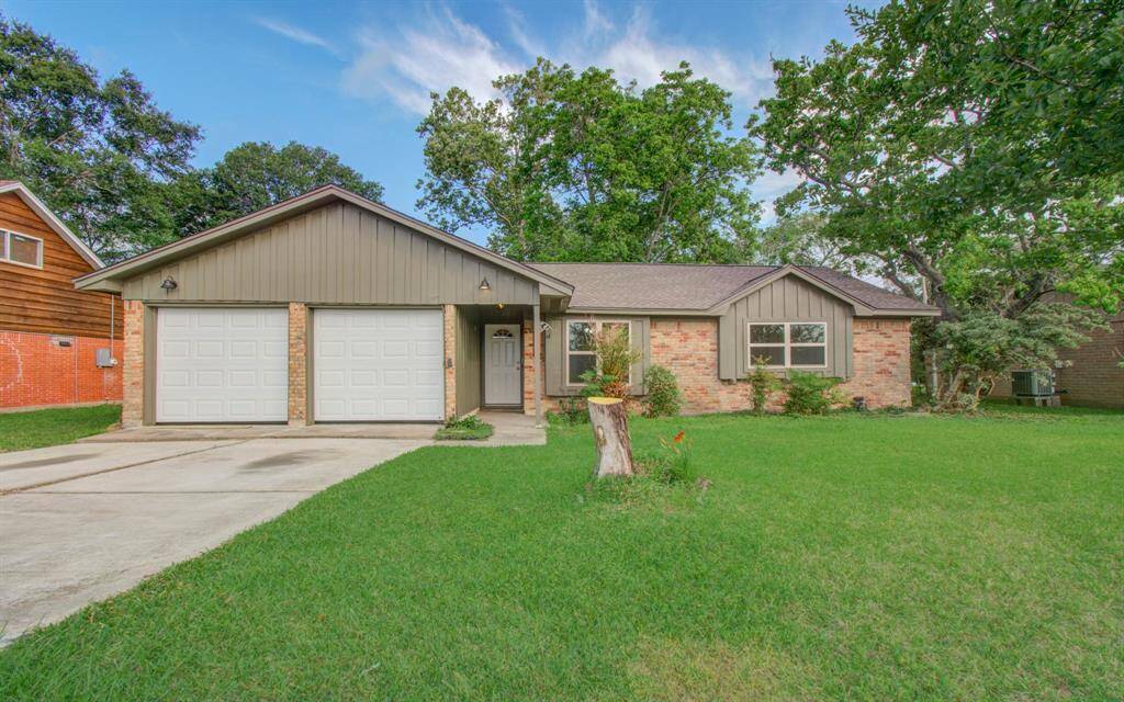 Charming single-story home with a brick facade and two-car garage. It features a well-maintained front lawn and mature trees, offering a welcoming and serene atmosphere.