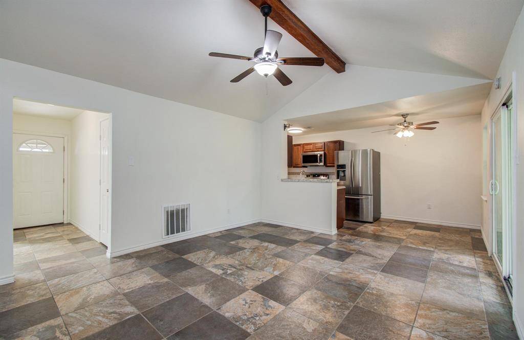 This photo showcases a bright, welcoming entryway with a tiled floor leading to a carpeted area. The space is well-lit with a simple ceiling light, and neutral walls provide a fresh, clean look.