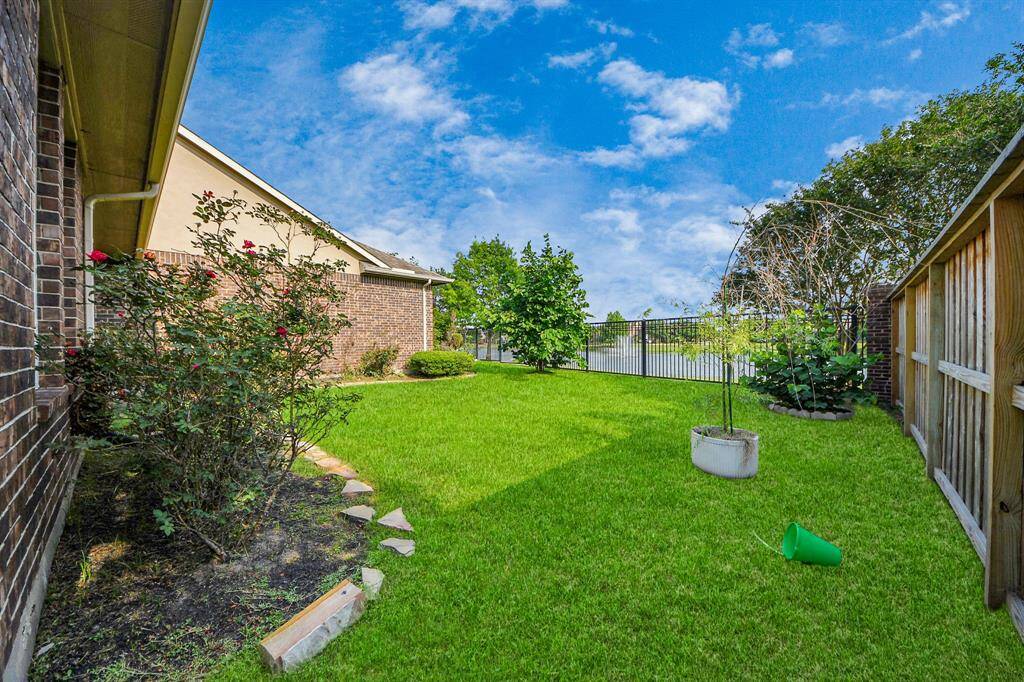 Backyard features mature shrubs and a small paved path, perfect for outdoor relaxation.