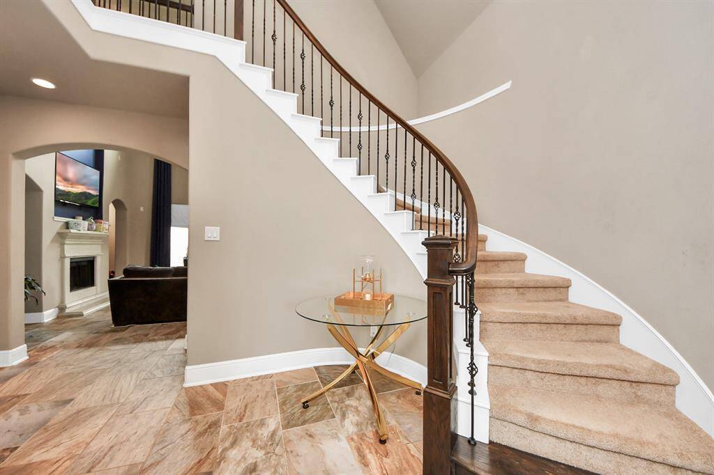 This inviting home features a curved staircase with elegant iron balusters and carpeted steps.