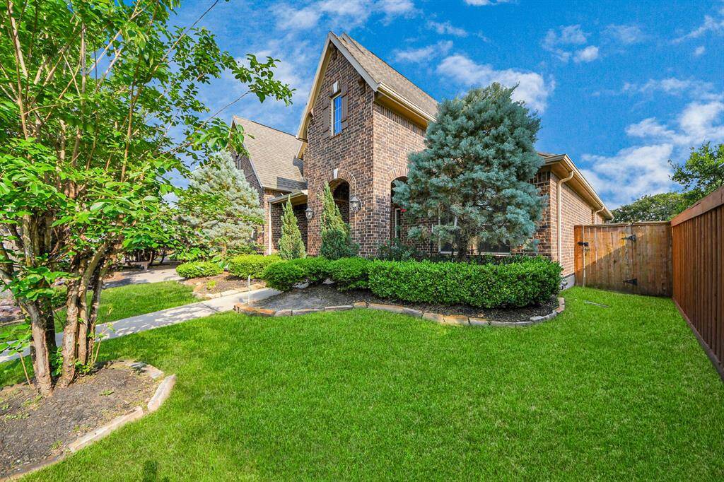 Charming brick home with well-maintained landscaping, lush green lawn, and mature trees. The inviting pathway leads to a cozy entrance, offering great curb appeal in a serene neighborhood.
