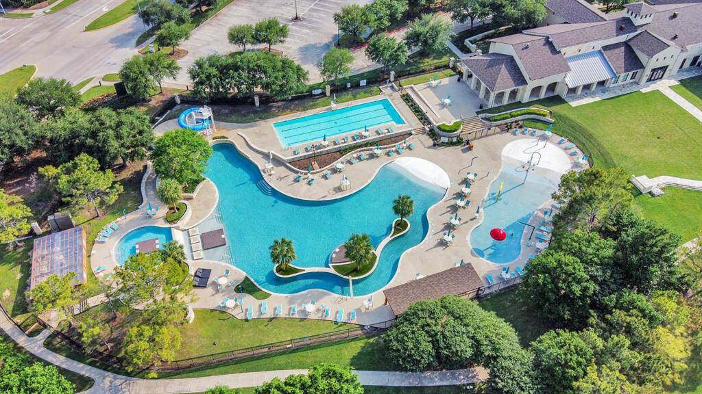 Luxurious community pool area with multiple pools, including a lap pool and a resort-style leisure pool. It features ample seating, lush landscaping, and a nearby clubhouse, providing a perfect spot for relaxation and recreation.