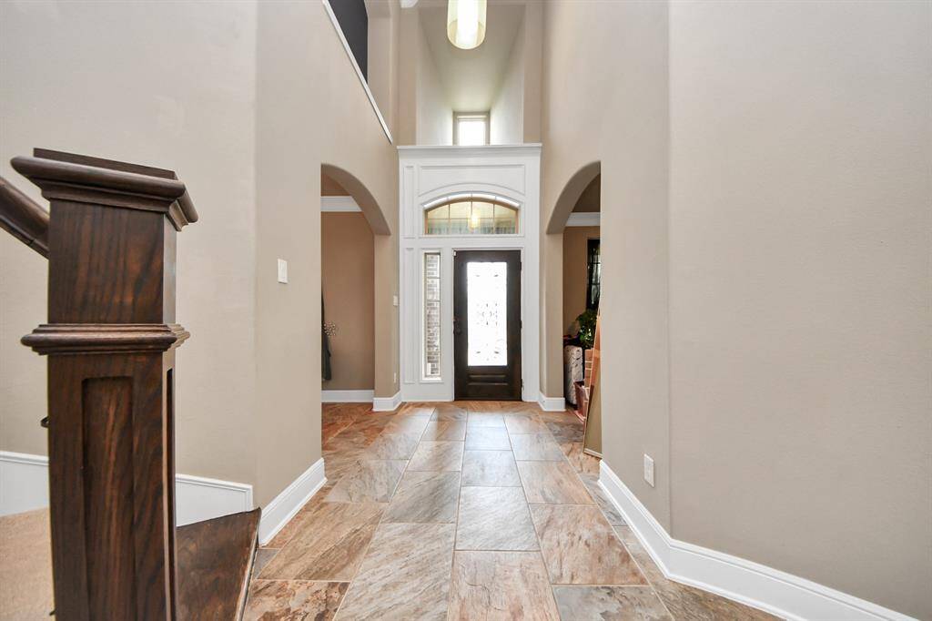 Spacious entryway with high ceilings, neutral walls, and tiled flooring.