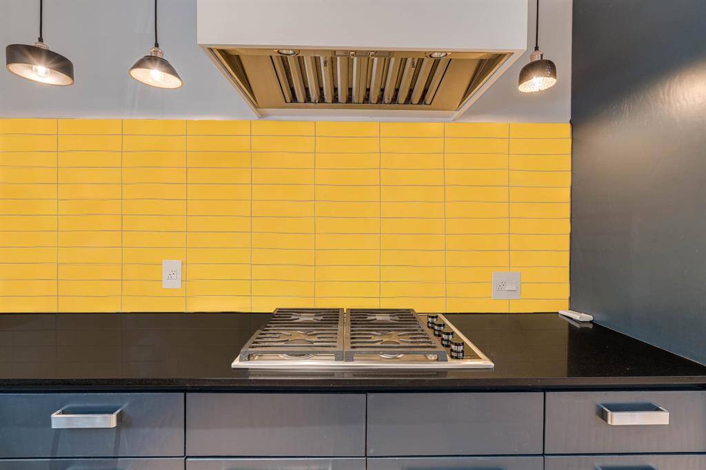 A bold yellow backsplash adds a vibrant pop of color and striking contrast, making a confident design statement