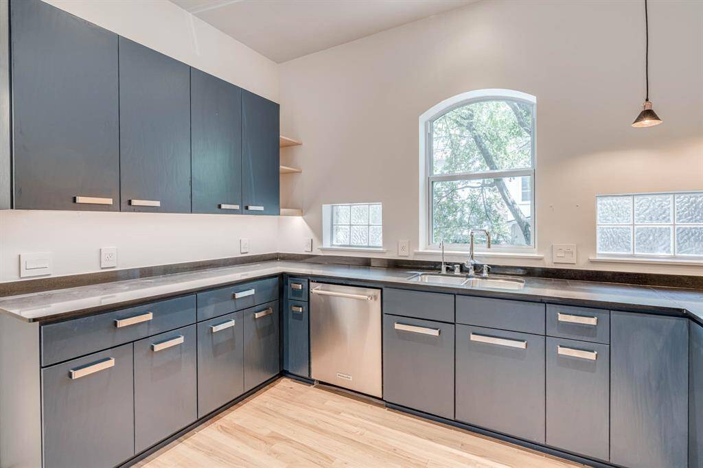The modern kitchen features sleek countertops and an under-mount sink perfectly positioned beneath a large window, allowing natural light to pour in while offering a serene view—making meal prep both functional and enjoyable