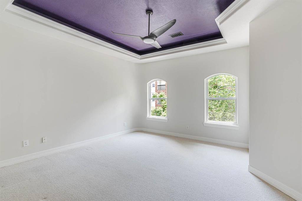 The primary bedroom, located on the top floor, features elegant slightly arched windows that bathe the space in natural light, creating a serene and airy retreat.