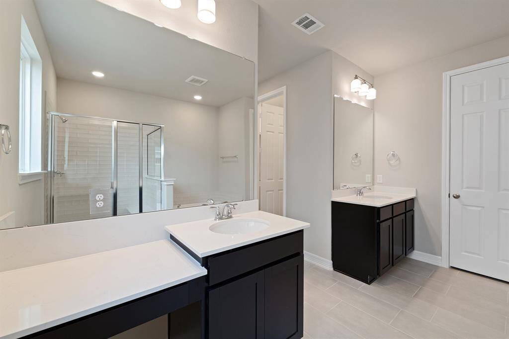 The en-suite bathroom offers a spa-like atmosphere with its elegant design, high end finishes, and tasteful lighting, creating a retreat within your own home.