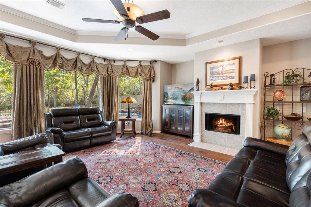 Welcome to the inviting family room, a perfect blend of warmth and style. This expansive space is designed for both relaxation and entertainment, featuring a stunning fireplace that serves as the room's centerpiece. Imagine cozy evenings by the fire, surrounded by the soft glow and warmth it provides. The room is further enhanced by a magnificent wall of windows, flooding the space with natural light and offering breathtaking views of the outdoors.