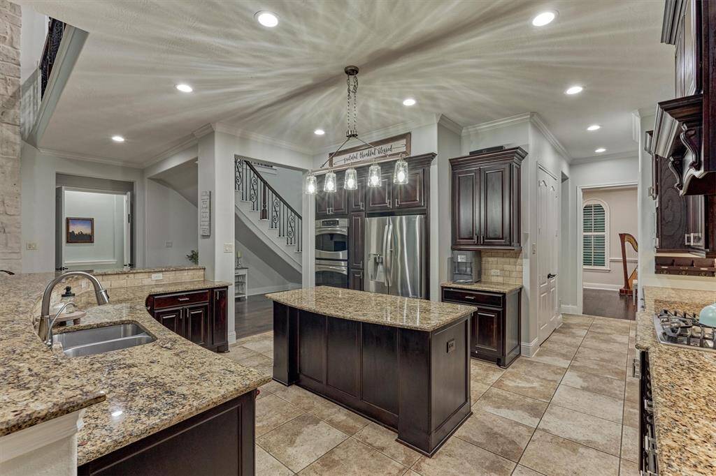 Kitchen boasts an island, J Kraft high end cabinets, granite countertops, gas cooktop, double ovens and large pantry.