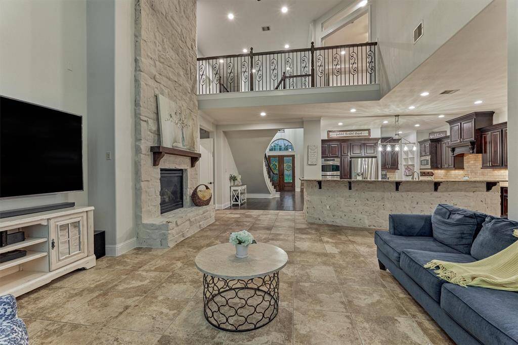 Two story family room with stone fireplace, tiled floors in the family room. Open and desirable floor plan