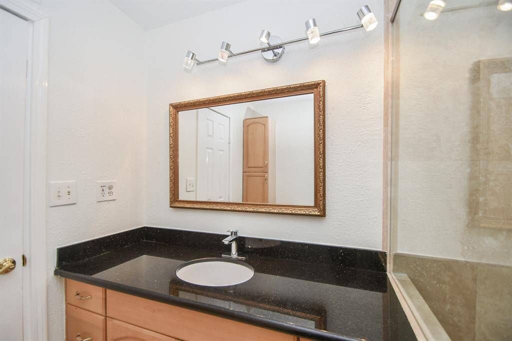 Primary bath with granite countertop and modern light and cabinet