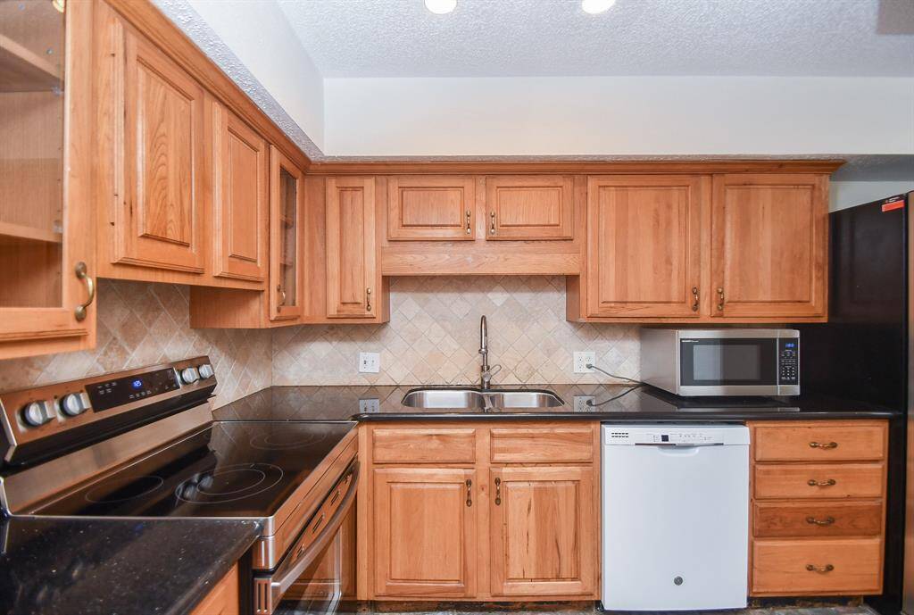 A view of the sink and new microwave. Plenty of cabinets in the kitchen.