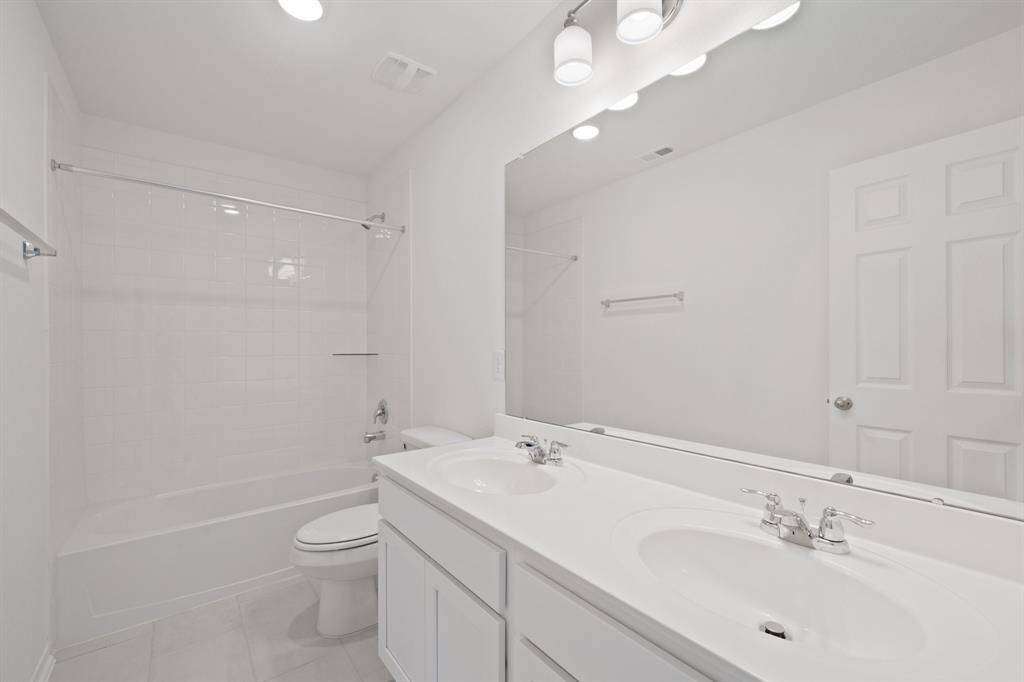 The secondary bath features tile flooring, white cabinetry and light countertops and a shower/tub combo. Perfect for accommodating any visiting family and friends.