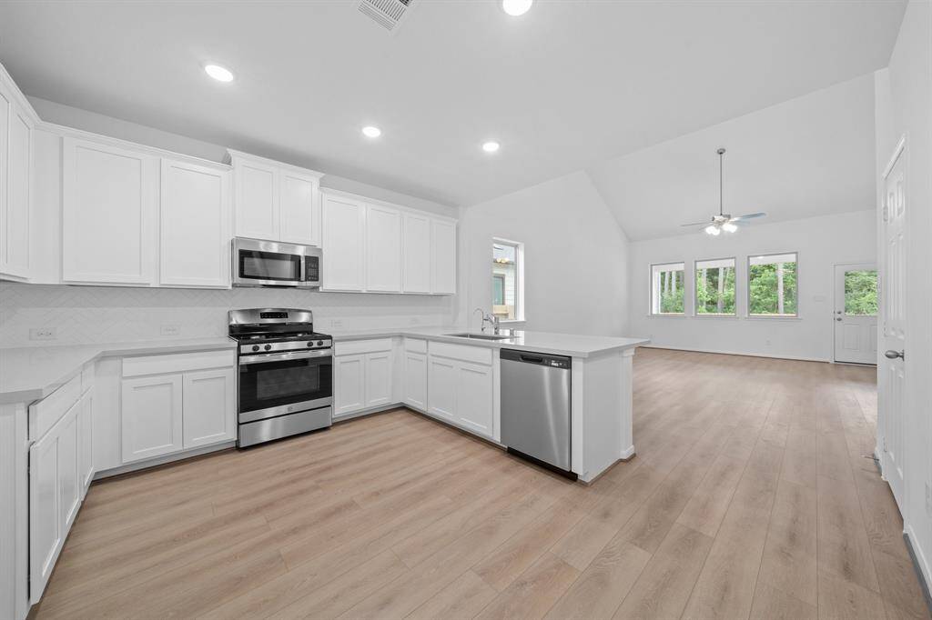 This light and bright kitchen features a large quartz island, white cabinets, a large sink overlooking your family room, recessed lighting, and beautiful backsplash.