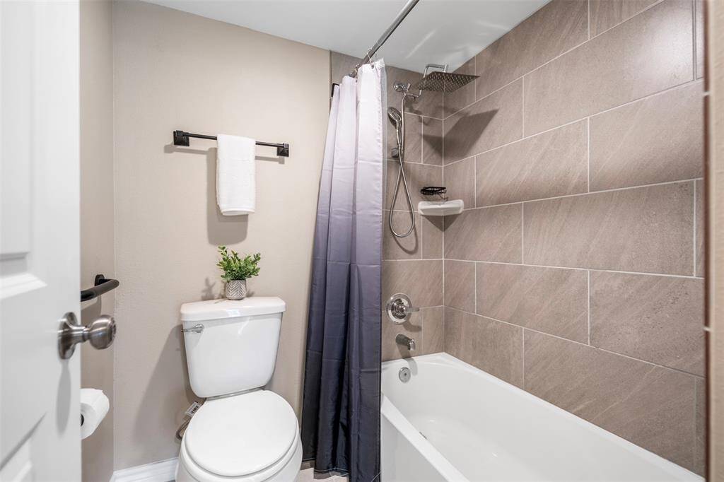 Stylish bathroom with a tub-shower combo, featuring lovely tile work throughout. The perfect blend of functionality and design, creating a relaxing space with modern finishes.