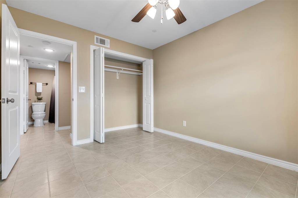 Another view of the secondary bedroom, highlighting its spacious layout with a glimpse of the hallway, nearby bathroom, and sizable closet—showcasing the well-connected and functional floor plan.