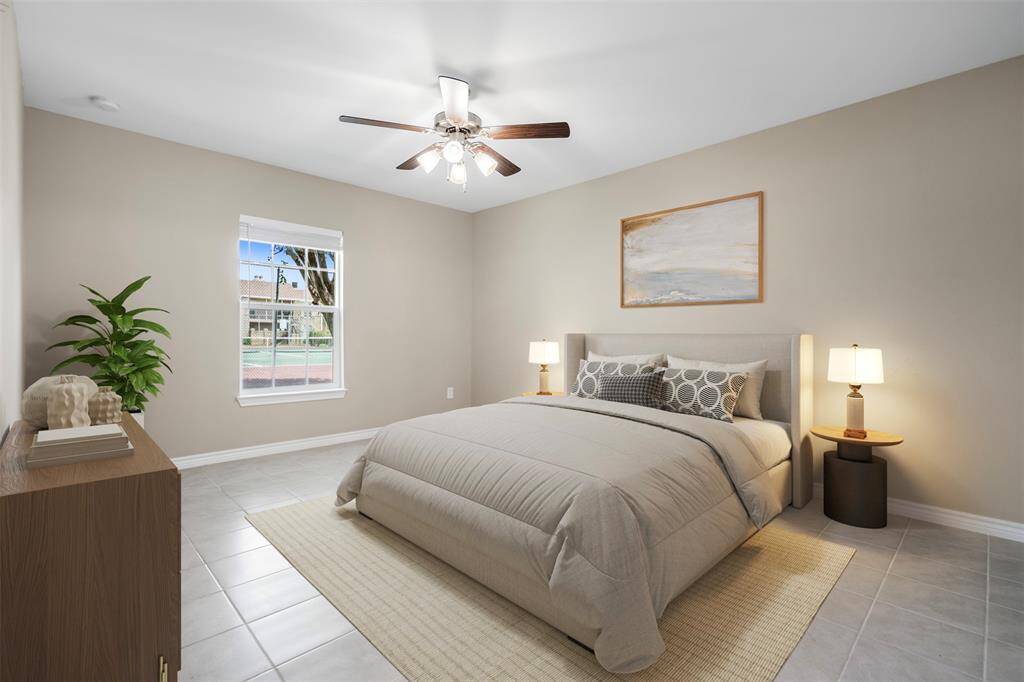 Spacious primary bedroom with tile flooring and an abundance of natural light, featuring an ensuite bath for added privacy and comfort—a peaceful retreat within the home.(This photo is virtually staged)