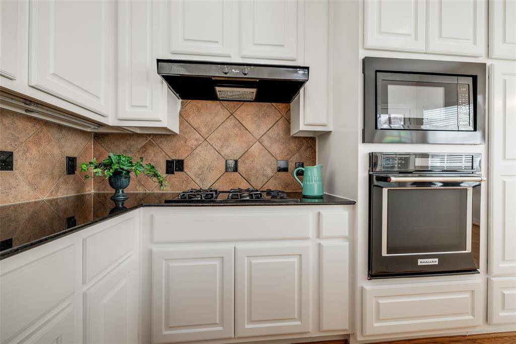 Gas cook top, single oven, microwave, white cabinets, black granire, tiled back slpash