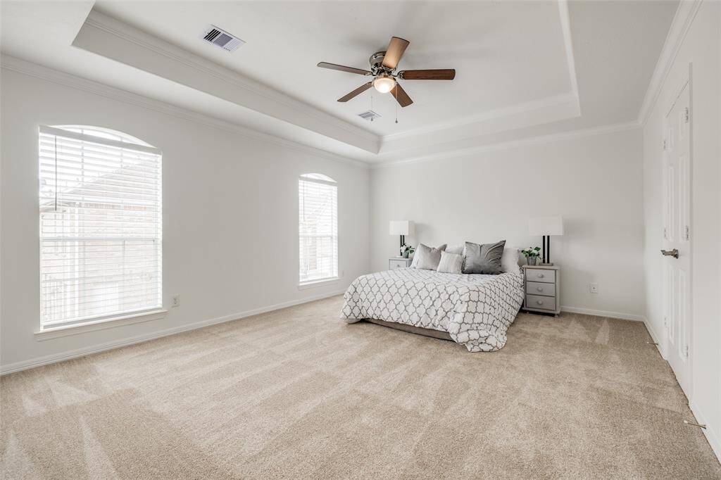Large Primary Bedroom suite with new carpet, ceiling fan, sitting area, tray ceiling with new ceiling fan