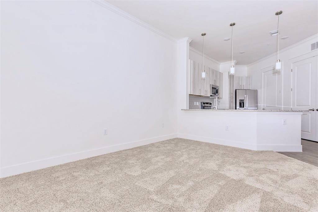 Kitchen with breakfast bar, modern white wood grain cabinetry, stainless steel appliances, soft-close drawers, and under cabinet lighting