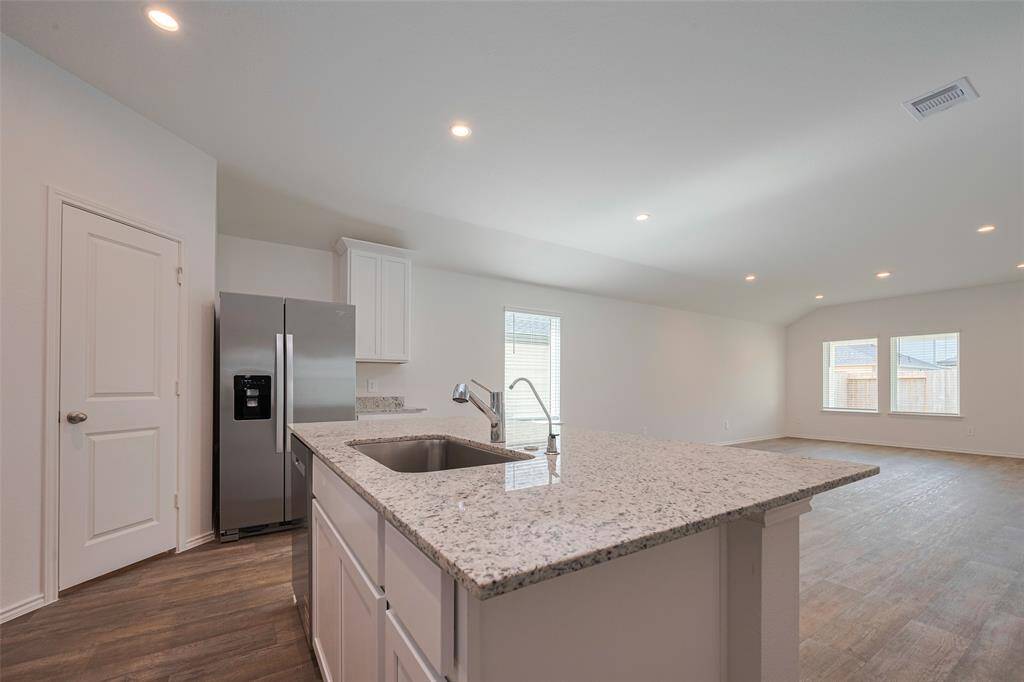 A central island anchors the kitchen, offering space for meal prep, casual dining, or conversation, all while incorporating a deep sink and sleek finishes.