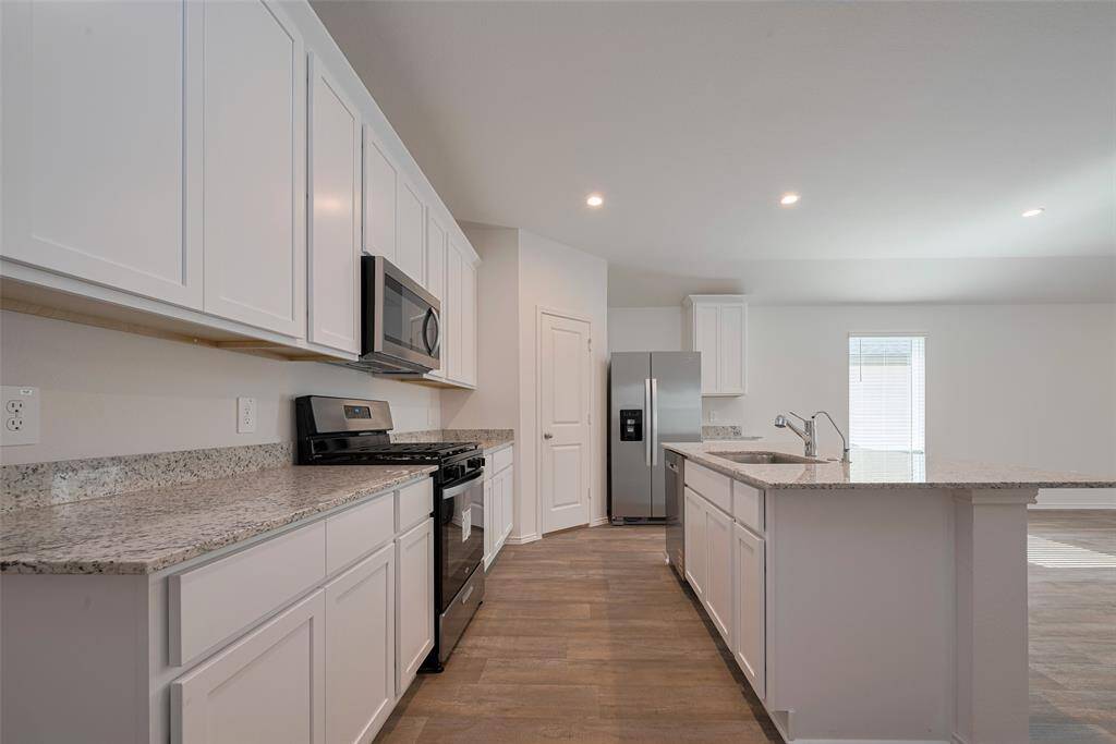 Bright white cabinetry lines both the upper and lower wall, paired with generous counter space to accommodate cooking essentials and showcase a clean, timeless design.