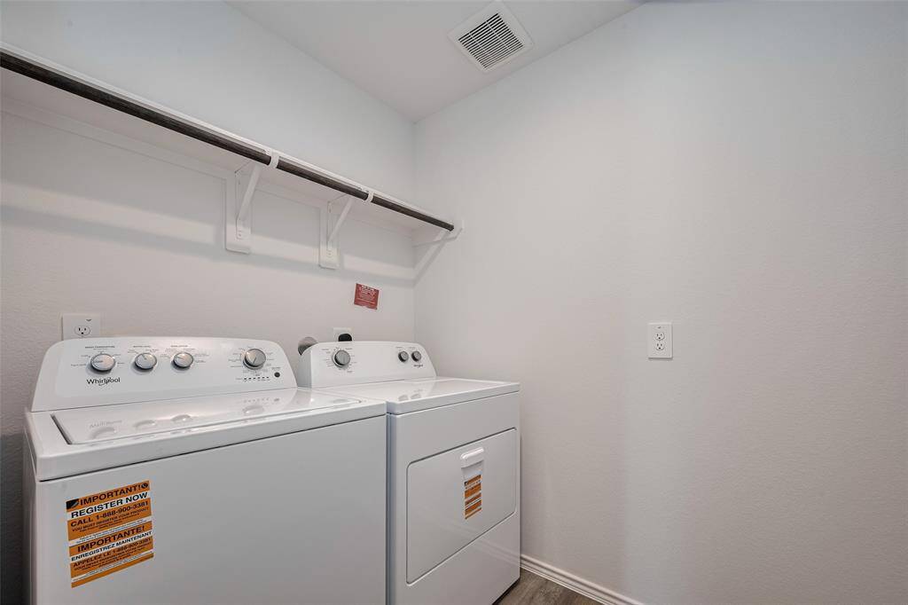 The laundry room features built-in shelving and a hanging rod over the washer and dryer—perfect for organizing and streamlining chores.