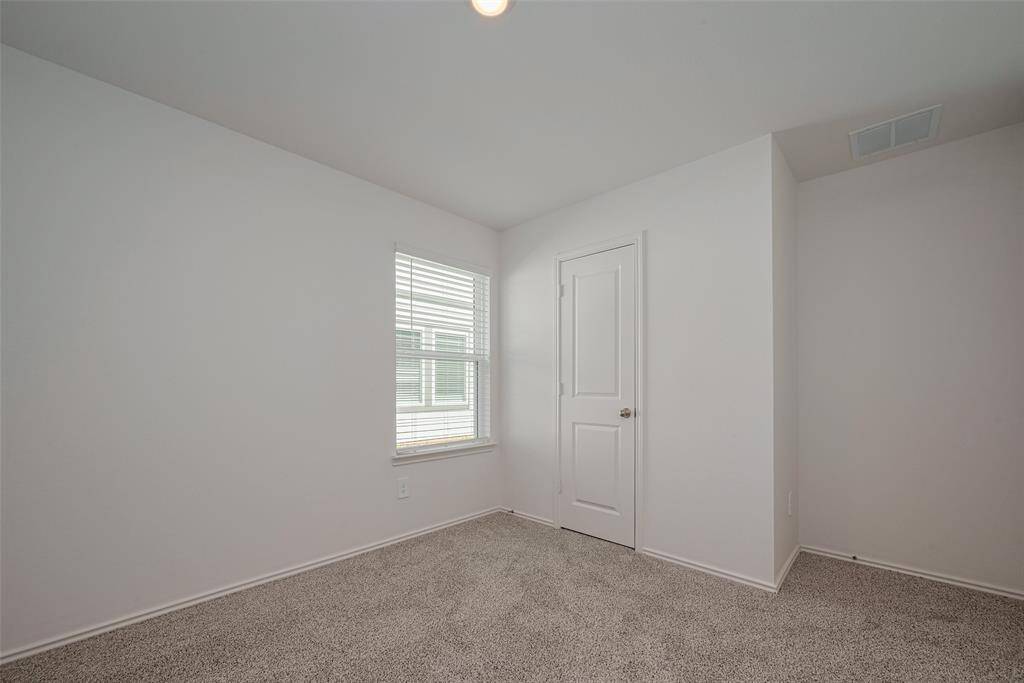 This carpeted bedroom offers soft neutral tones and a large window that fills the space with light—an ideal retreat or flexible space for work or guests.