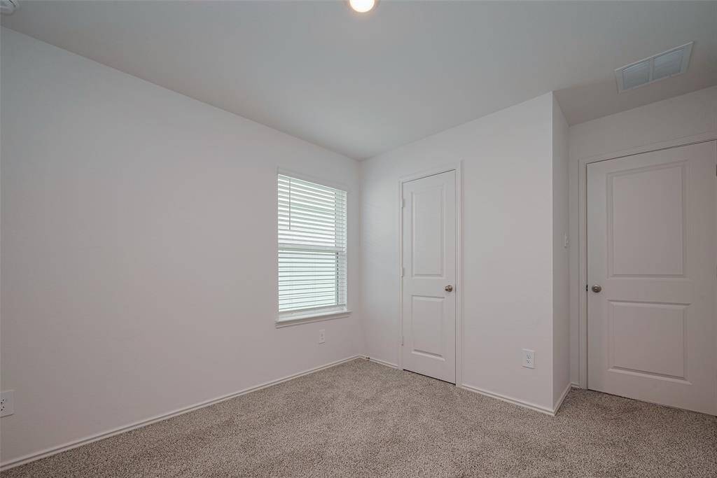 The third bedroom continues the cohesive design, offering a peaceful atmosphere with natural light, cozy carpeting, and ample space for personal style.