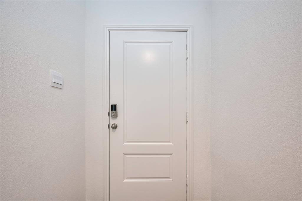 From inside, the front door is framed by a softly lit foyer, setting a welcoming tone with clean lines and neutral finishes that complement the home’s modern aesthetic.