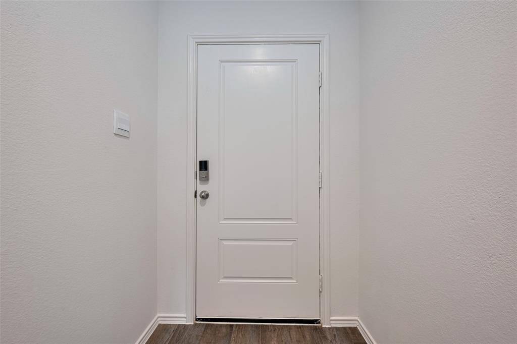 Bathed in natural light from large windows and a glass-paneled door to the backyard, the living room is bright and airy. Recessed lighting and warm-toned flooring add a cozy, modern finish.
