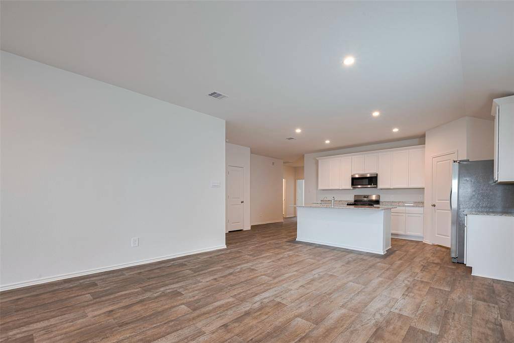 Sleek white cabinetry above and below provides ample storage, while generous countertops offer space to prep, serve, and enjoy. The clean design enhances the kitchen’s streamlined appeal.
