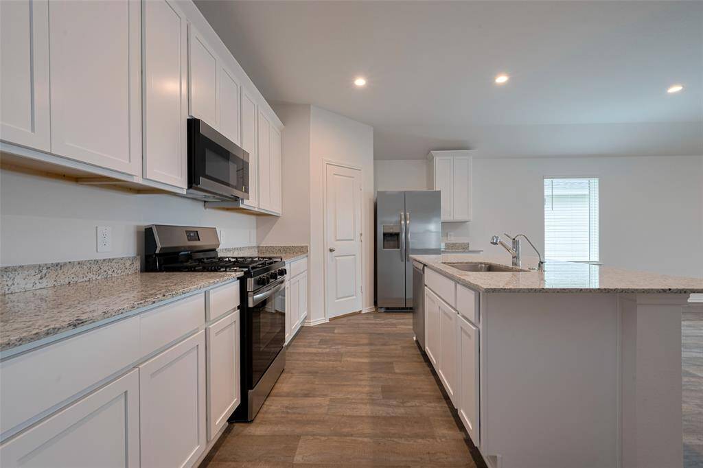A central island anchors the kitchen, complete with an inset sink and room for seating—perfect for quick meals, casual conversations, or entertaining while cooking.