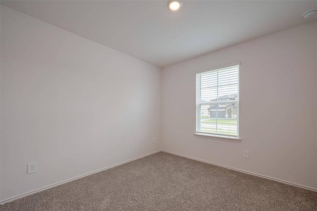 Similar in layout and finish, this second bedroom offers plush carpeting, a window, and quiet comfort—ideal for guests, work, or rest.