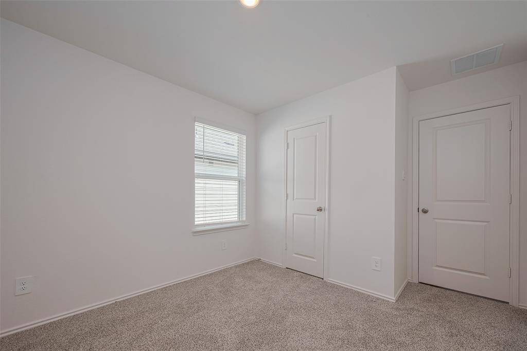 The third bedroom mirrors the home’s cohesive style, with warm carpeting underfoot and a large window welcoming in natural light.