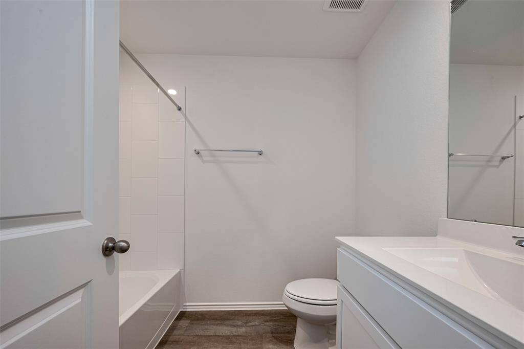 This full bathroom showcases a clean, classic look with a white vanity, mirror above, and a tiled tub-and-shower combo that balances utility with style.