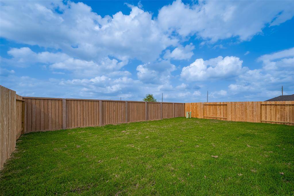 The expansive backyard is fully fenced and blanketed in vibrant green grass—offering a perfect canvas for play, gardening, or future outdoor additions.