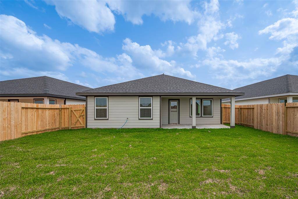 The covered patio provides generous space for outdoor seating or dining, with views of the lush backyard.