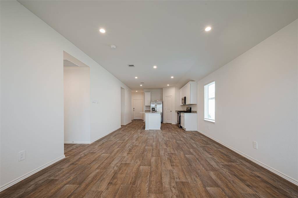The main living space unfolds in a spacious open layout that seamlessly connects the kitchen, dining area, and living room. Clean sightlines and continuous flooring enhance the sense of openness.