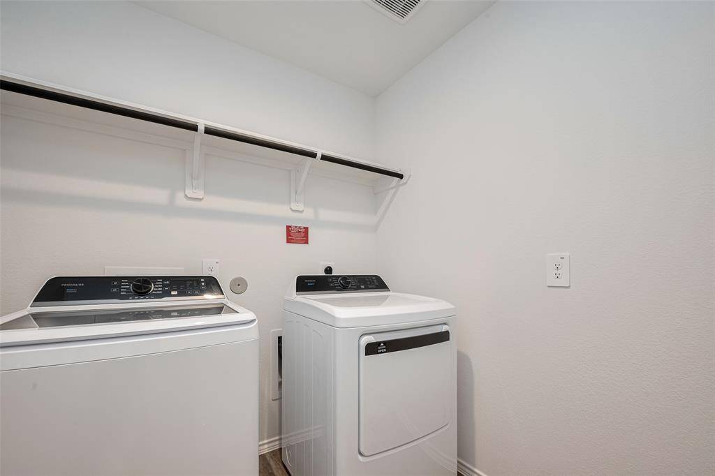 The laundry room is thoughtfully outfitted with a built-in rack and hanging rod above the washer and dryer area.