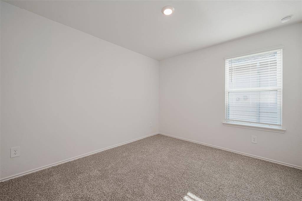 Similar in size and finish, the second bedroom also features plush carpeting, a wide window, and a soothing color palette perfect for relaxation or creativity.