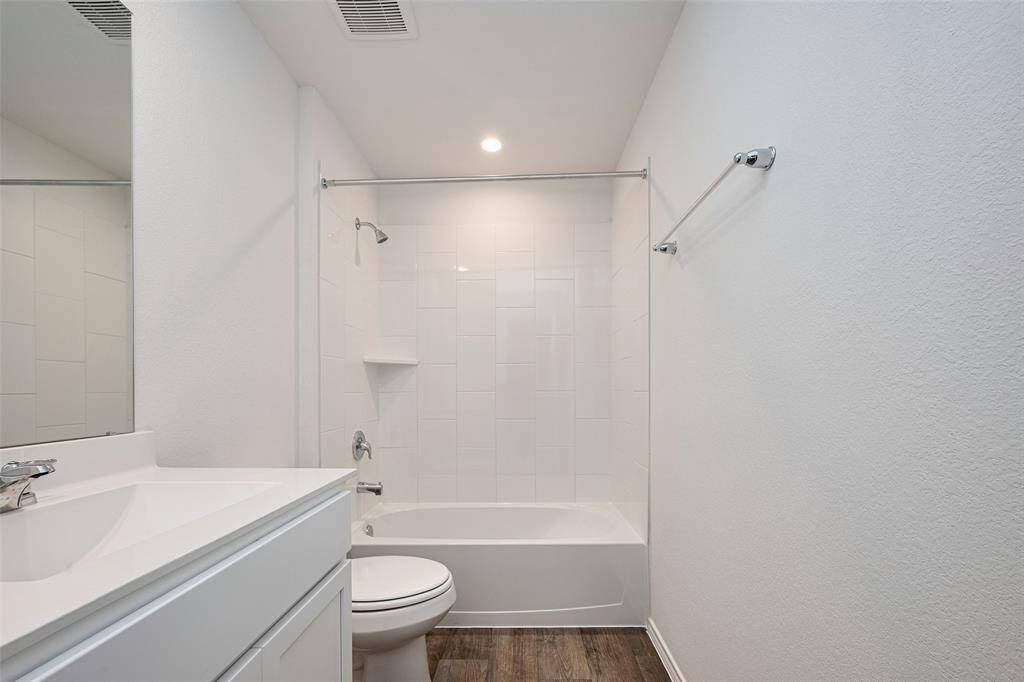 This full bathroom is cleanly styled with white tiling and a shower-tub combo. The white vanity offers under-cabinet storage and a wide mirror for everyday convenience.