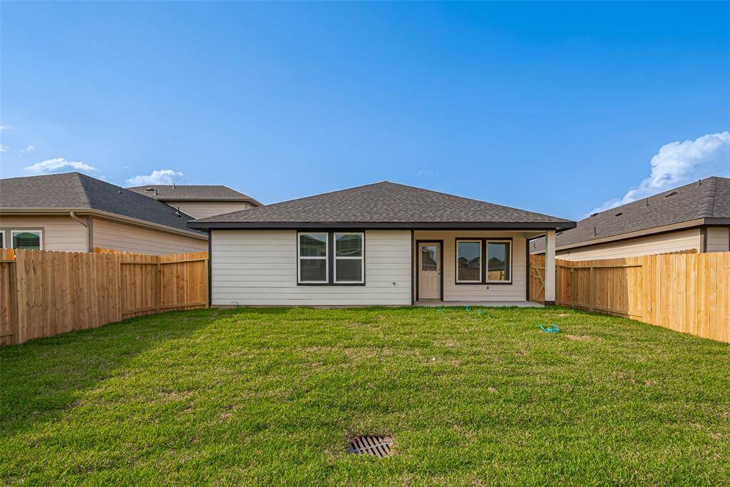 The covered patio at the back of the home provides shaded space for lounging or dining, with open views of the vibrant backyard.