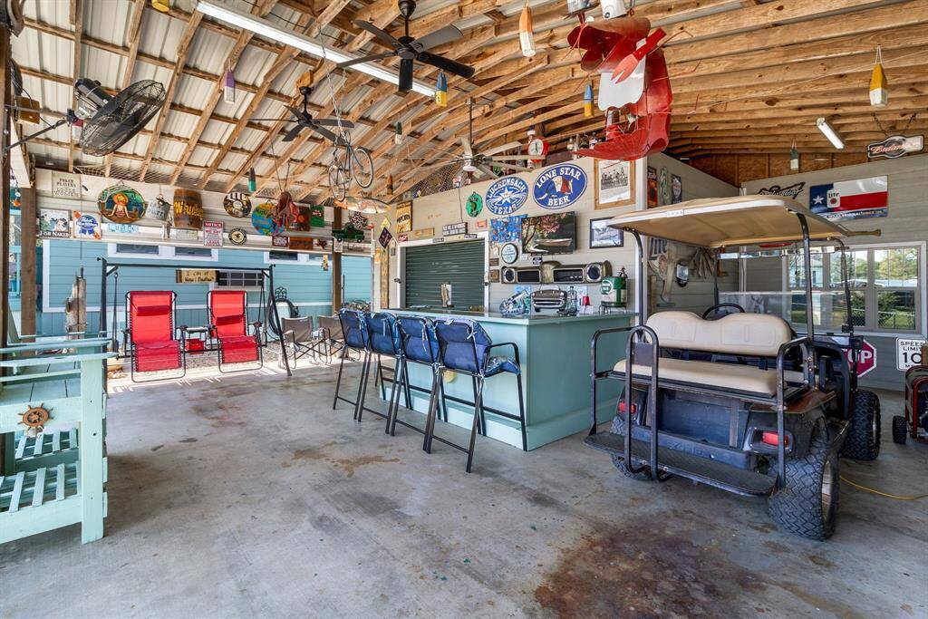 The covered patio is a combination of work and fun. There's a built-in bar, and a golf cart is parked inside, so you have a lot of space to entertain friends, work on projects, or even a little bit of both!