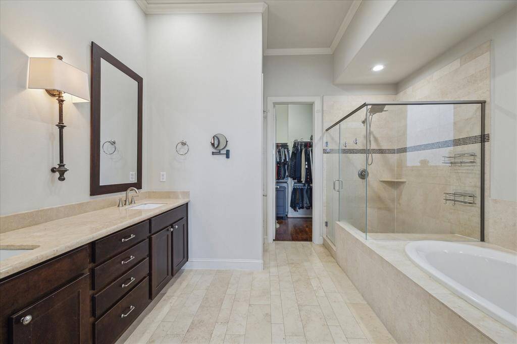 Double sinks with large glassed walk-in shower and separate soaking tub. One of two closets.