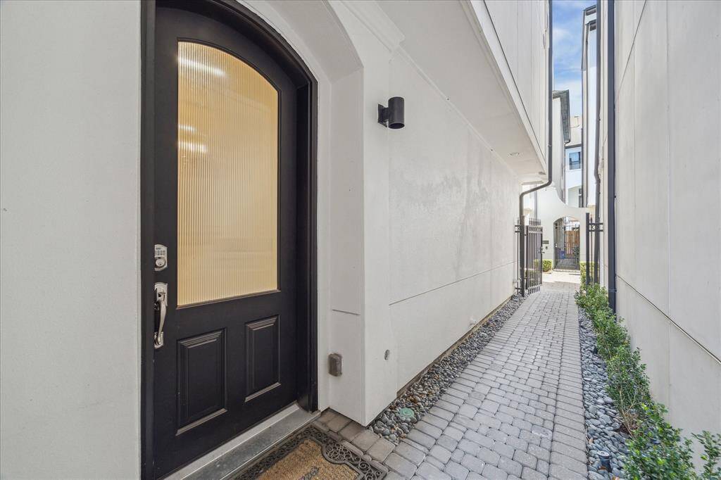 Entry door is behind a wrought-iron gate down a stone walkway.