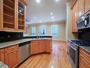 This view showcases the SS appliance package and thoughtful cabinetry features, including a pull-out trash can drawer (to the left of the dishwasher), a corner lazy Susan cabinet (far left of the photo), and a tall lower cabinet to the right of the sink, perfect for storing baking sheets and large cutting boards.