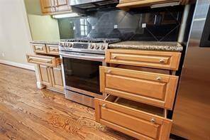 Storage galore! This view highlights the abundant storage options, featuring specialty drawers for pots, pans, and spices thoughtfully placed next to the 5 burner gas range for convenient access.