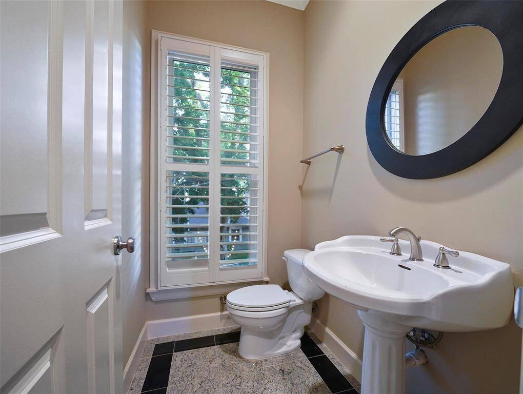 Conveniently tucked away from the living area on the second floor landing is this guest bathroom featuring a pedestal sink, an 8ft solid core door, and high-end plumbing hardware, fixtures, double crown molding, and granite flooring. A wide widow offers views of trees and nature.