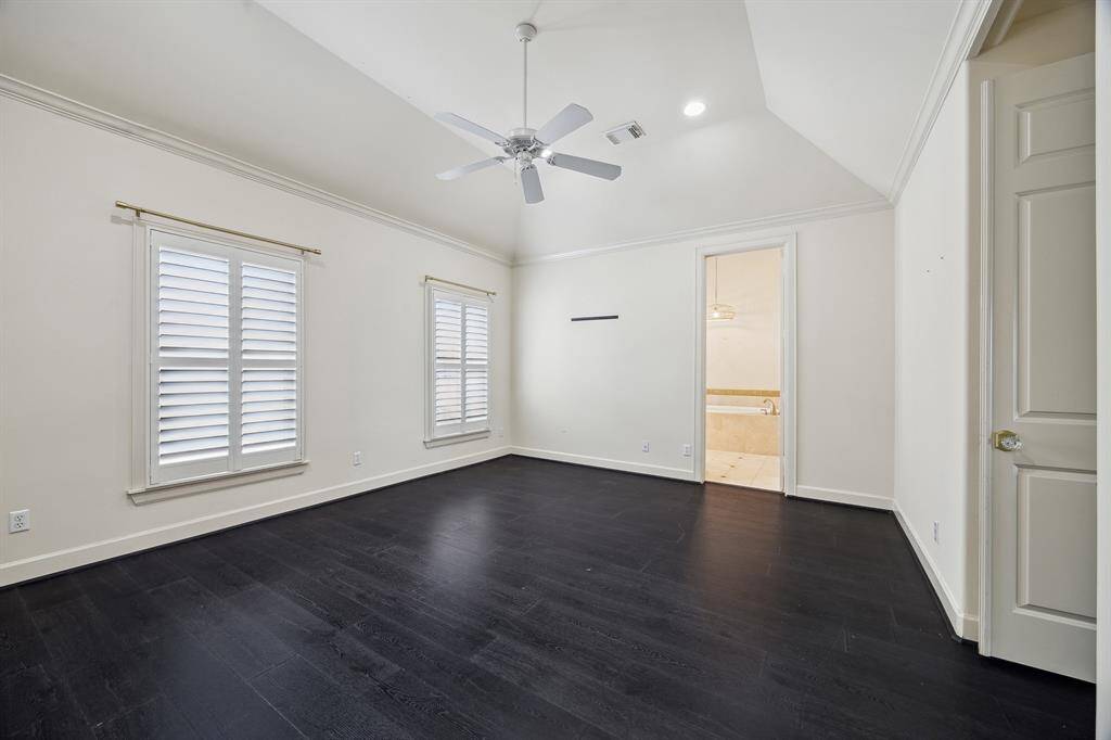 The spacious primary bedroom features a vaulted ceiling with a ceiling fan, and abundance of natural light and his/her walk-in closets.